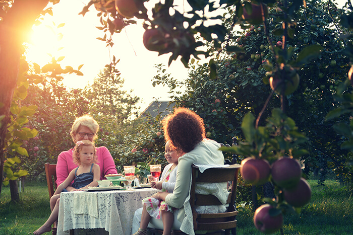 Outdoor scene featuring multiple generations of women around a table